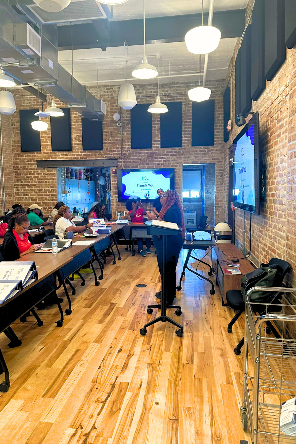 Niki Da'Jon, MBA, standing at the center of a room and speaking to educators during a consulting workshop.